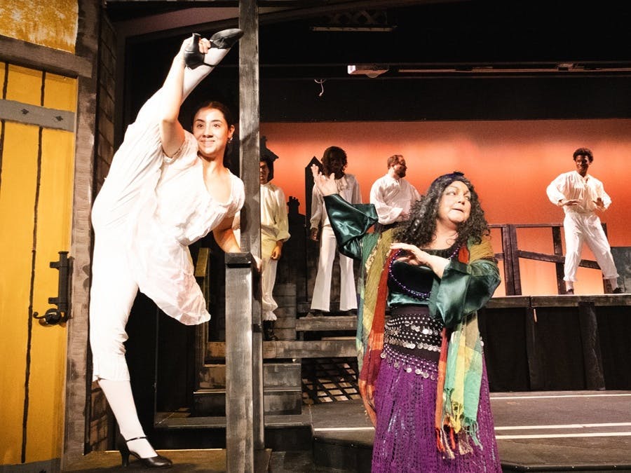 Production of Something Rotten featuring Nostradamus pointing to a dancer with leg extended overhead	